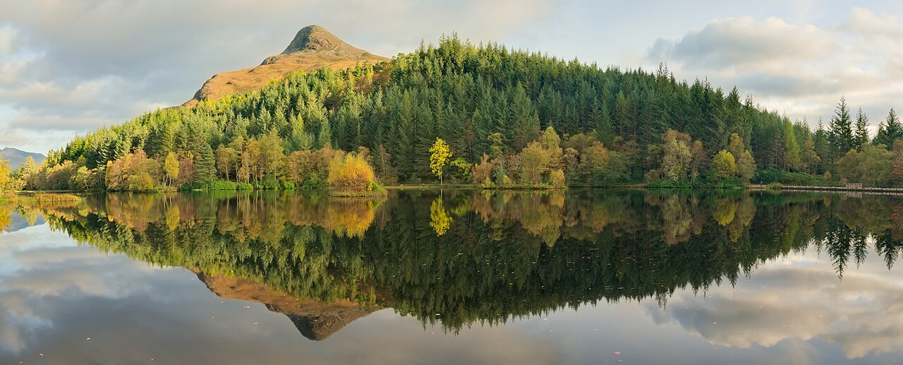 Mountain lochan at golden hour with glassy water reflections